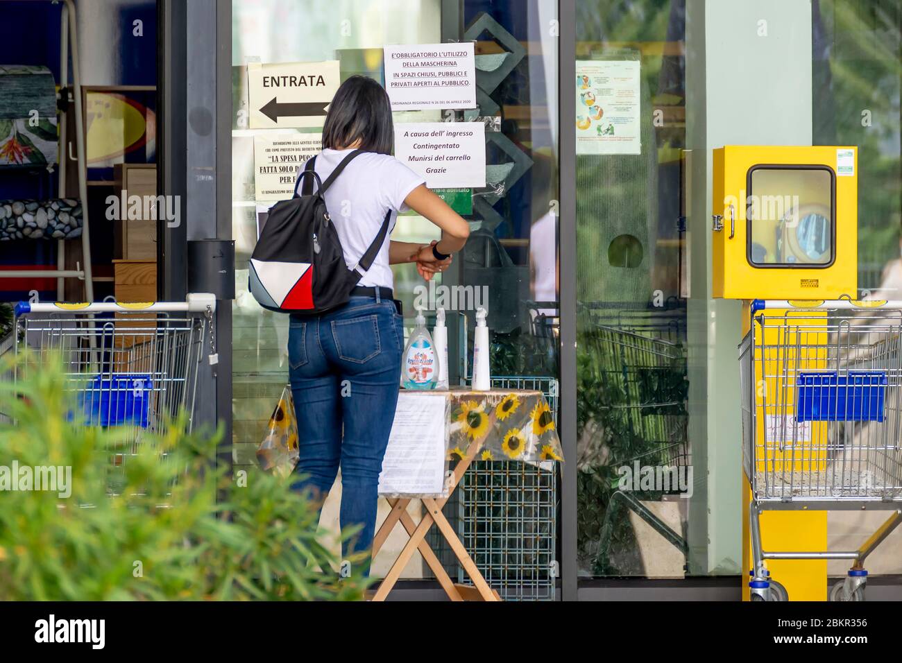 Une femme se désinfecte les mains avec un gel spécial à l'entrée d'un supermarché, conformément aux nouvelles réglementations en raison de la pandémie du coronavirus Covid-19 Banque D'Images