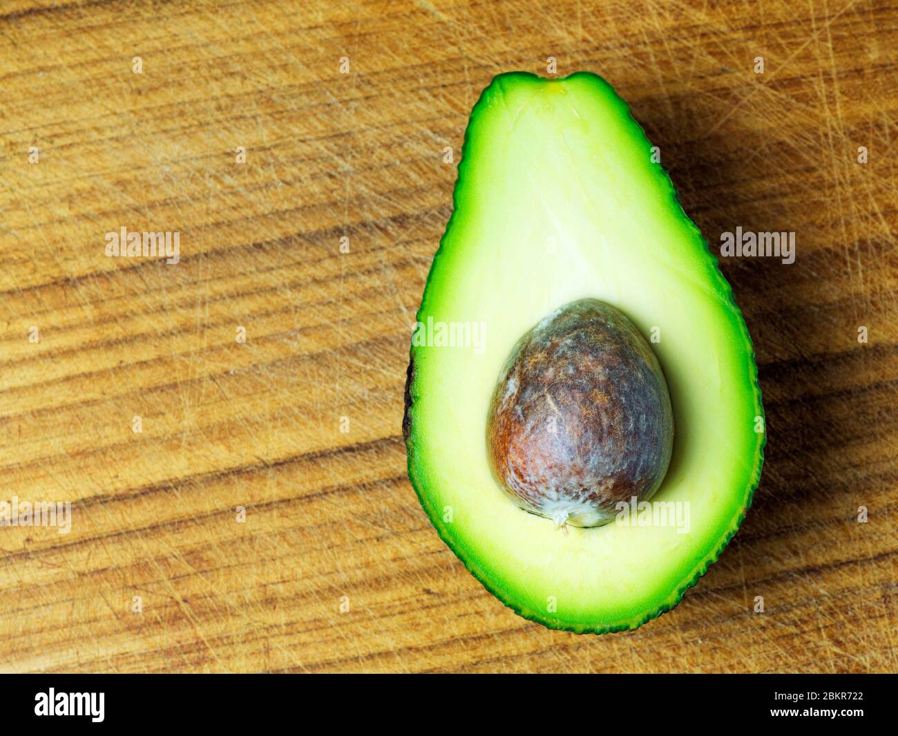 Un demi avocat avec la pierre laissée sur une planche à découper en bois Banque D'Images