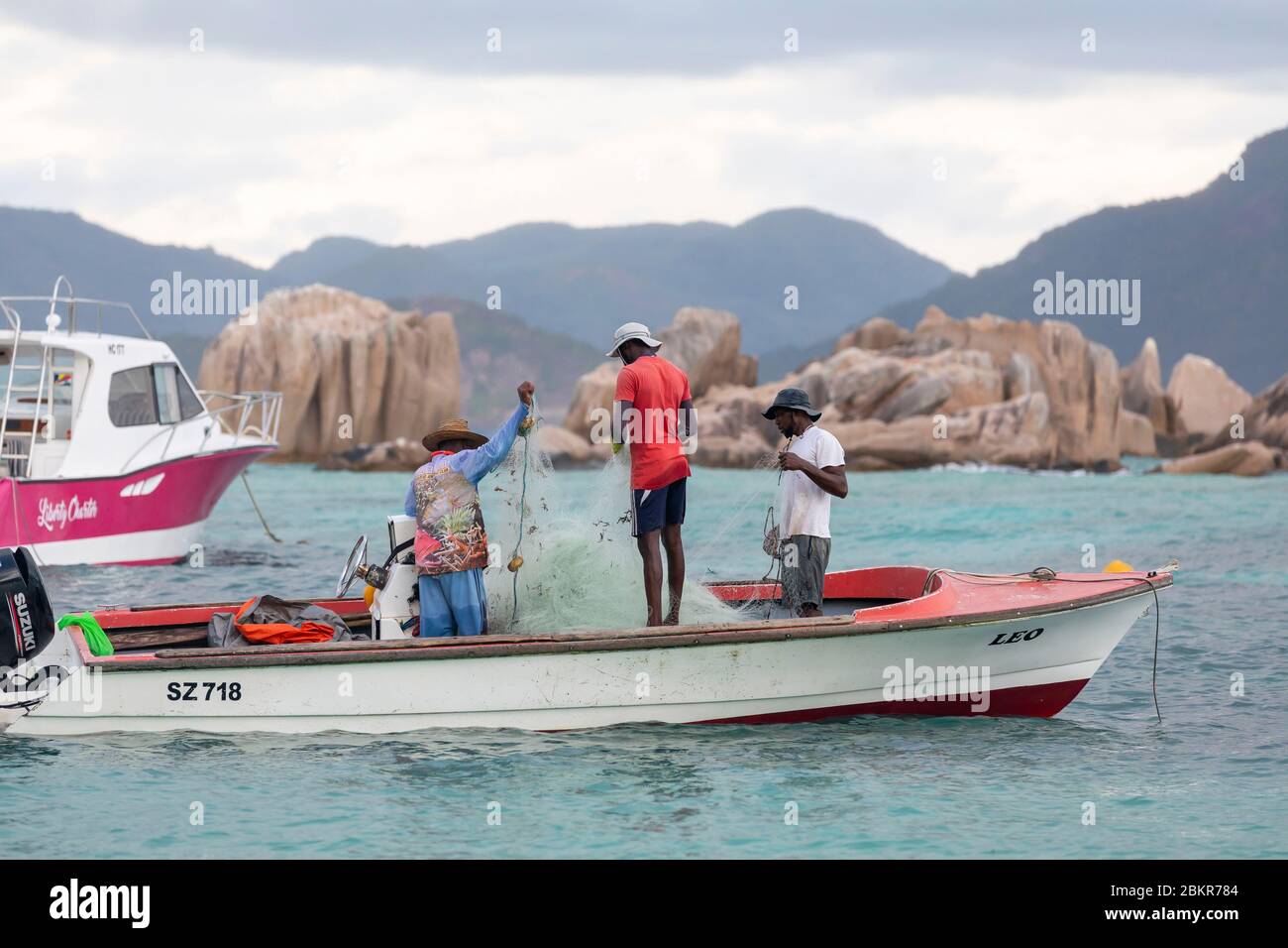 Seychelles, île de Digue, bateau de pêche à l'ancre devant les rochers granit Banque D'Images