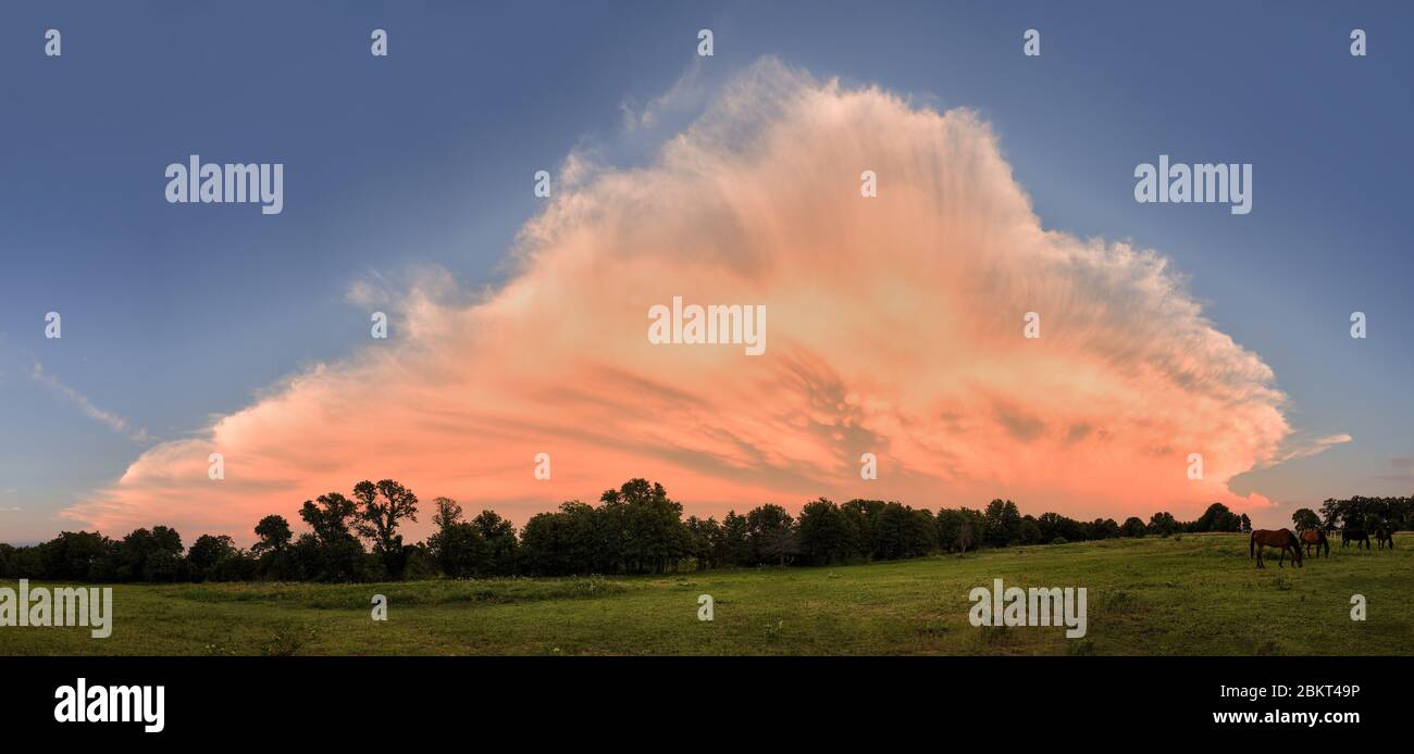 Grand nuage d'orage se dissipant sur un paysage rural, avec la dernière lumière de coucher du soleil le colorant rose et orange Banque D'Images