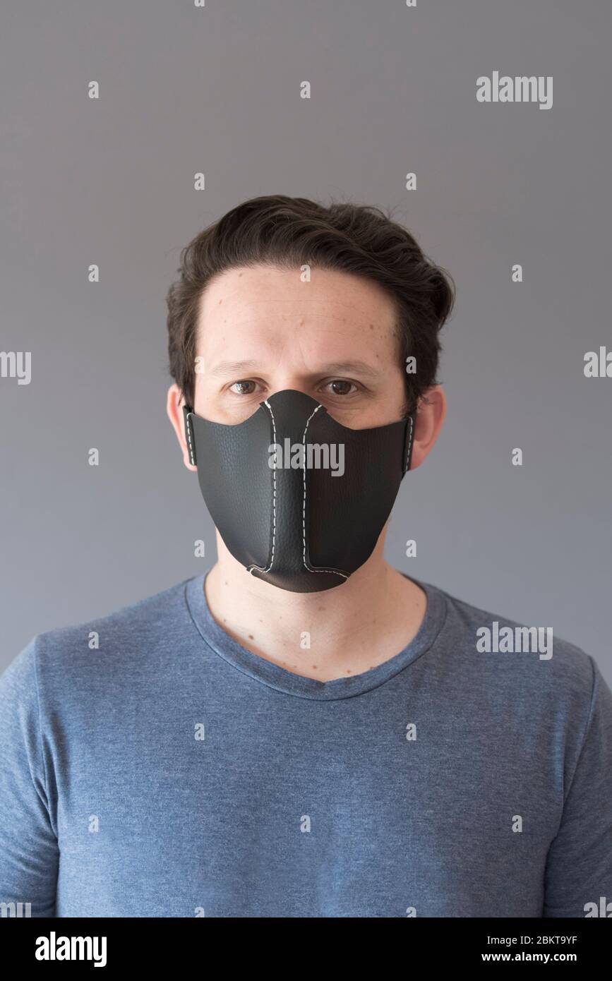Portrait avant d'un jeune homme portant un masque de protection en cuir synthétique réutilisable fait maison, pour prévenir la propagation de la maladie du coronavirus, dans Banque D'Images