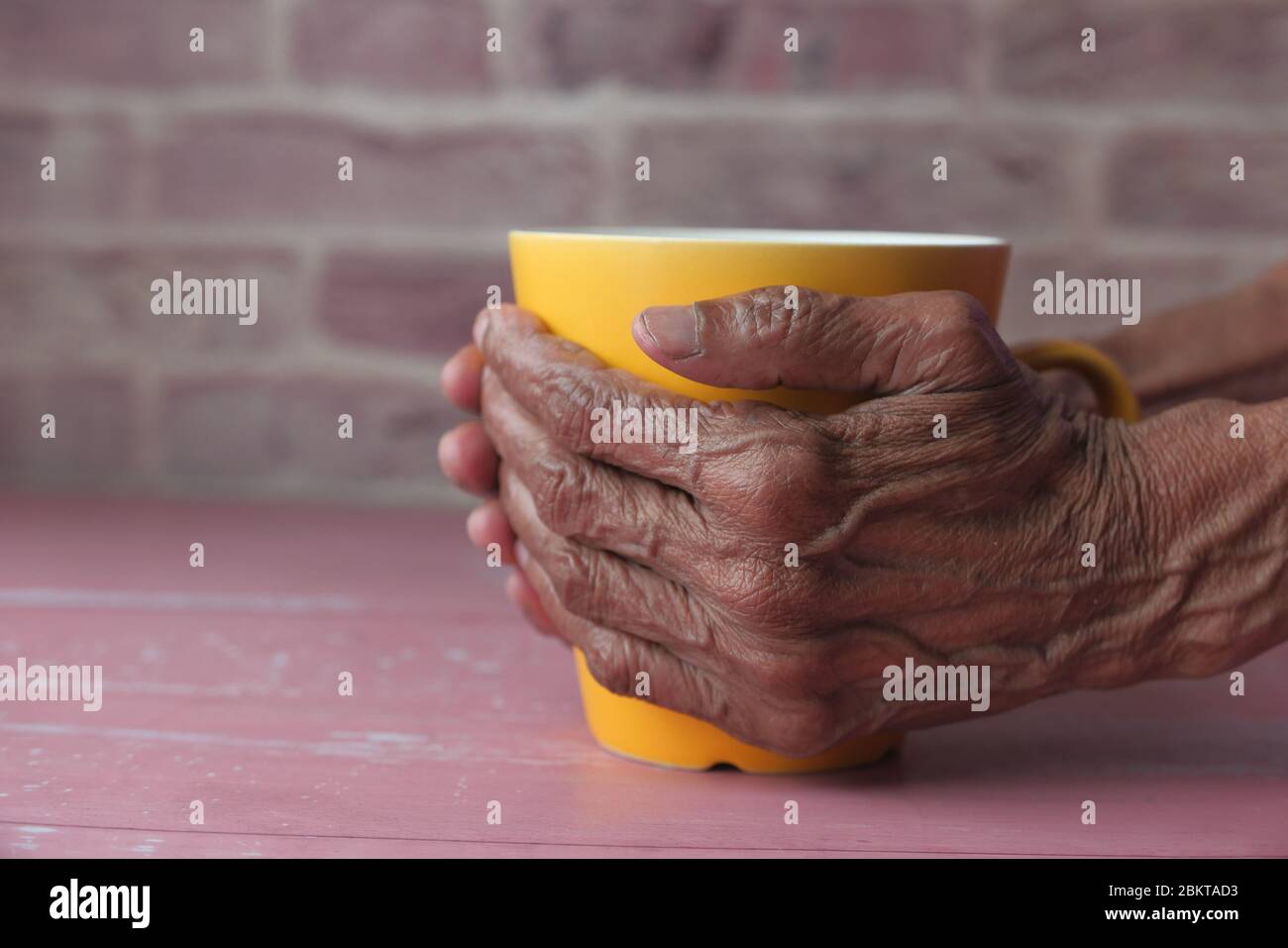 Gros plan de la main des femmes âgées tenant une tasse. Banque D'Images