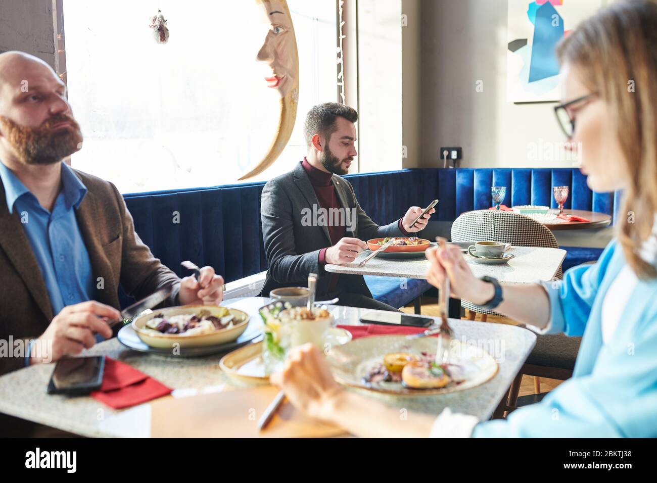 Un beau jeune homme d'affaires qui mange de la salade et qui s'est servi du téléphone dans un café moderne Banque D'Images