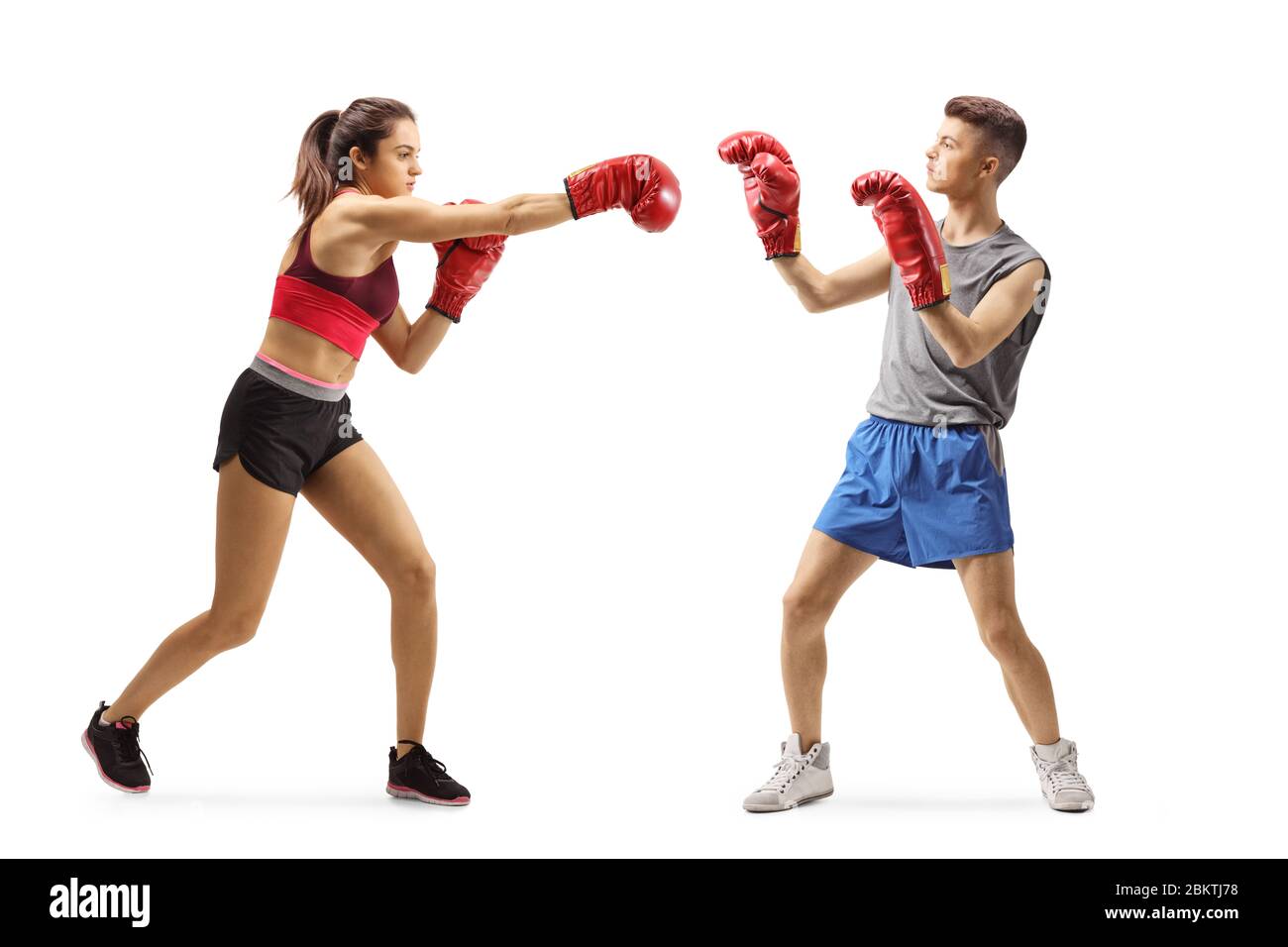 Prise de vue en longueur d'une jeune fille et d'un gars de sportswear qui se battent avec des gants de boxe isolés sur fond blanc Banque D'Images