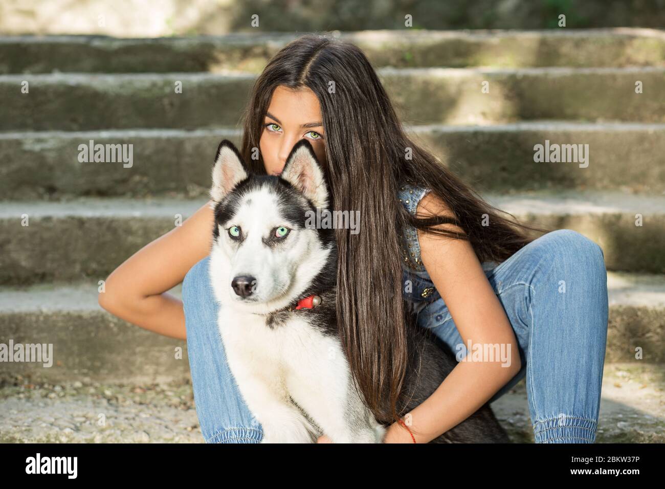 Jolie femme et son animal de compagnie. Elle a nagé avec son chien husky, isolé des escaliers gris en béton urbain sur fond d'escaliers, tous deux regardant la caméra. Tak Banque D'Images