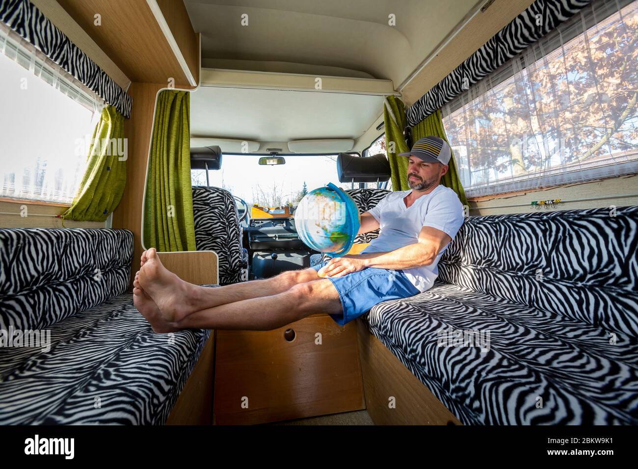 Portrait d'un homme imprudent pendant les vacances assis dans son van regardant un globe Banque D'Images