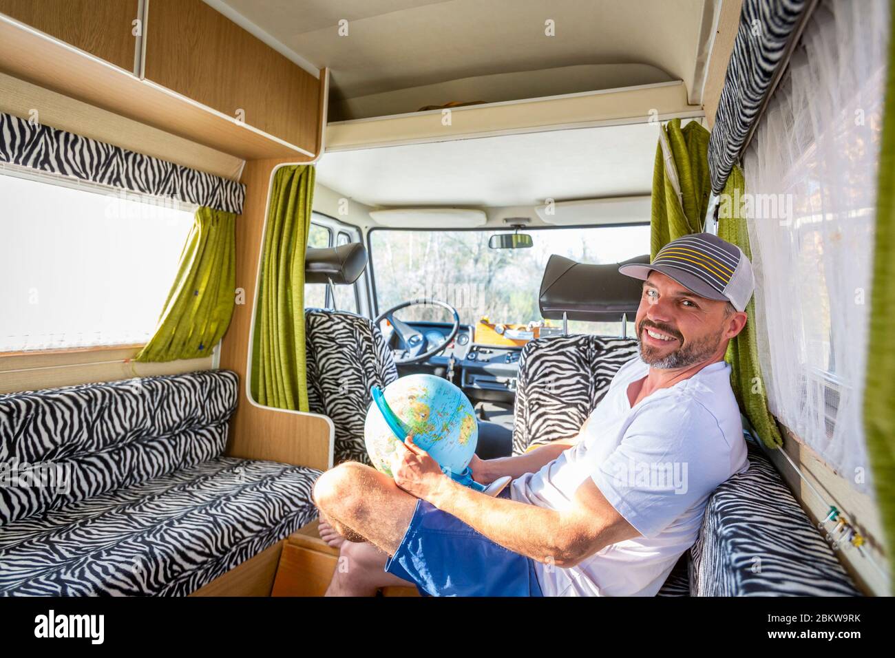 Portrait d'un homme imprudent pendant les vacances assis dans son van regardant un globe Banque D'Images