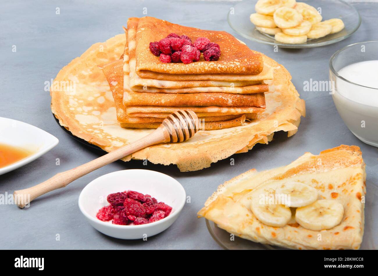 Crêpes aux baies, au miel et aux bananes pour le petit déjeuner sur fond rustique gris blanc Banque D'Images