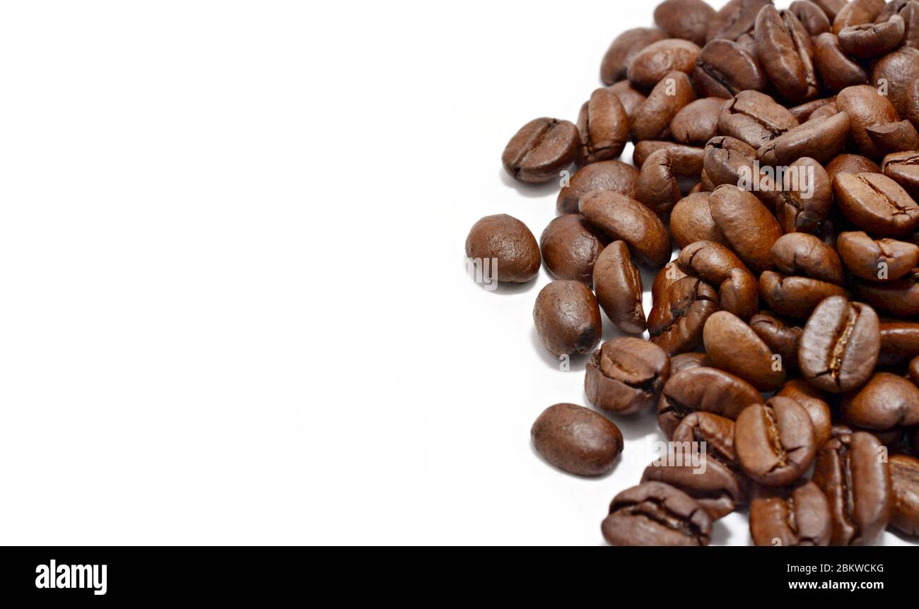 Tas de grains de café sur fond blanc avec espace de copie sur la gauche. Banque D'Images