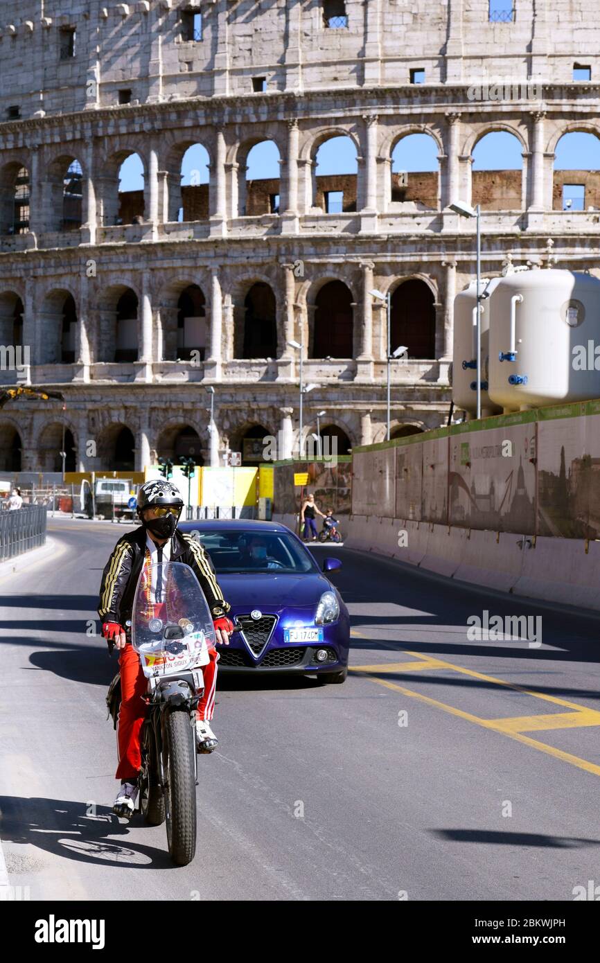 Homme portant un masque médical, sur les passes à moto devant le Colisée pendant le verrouillage du coronavirus de l'oit Covid 19. Rome, Italie, Europe, UE. Banque D'Images