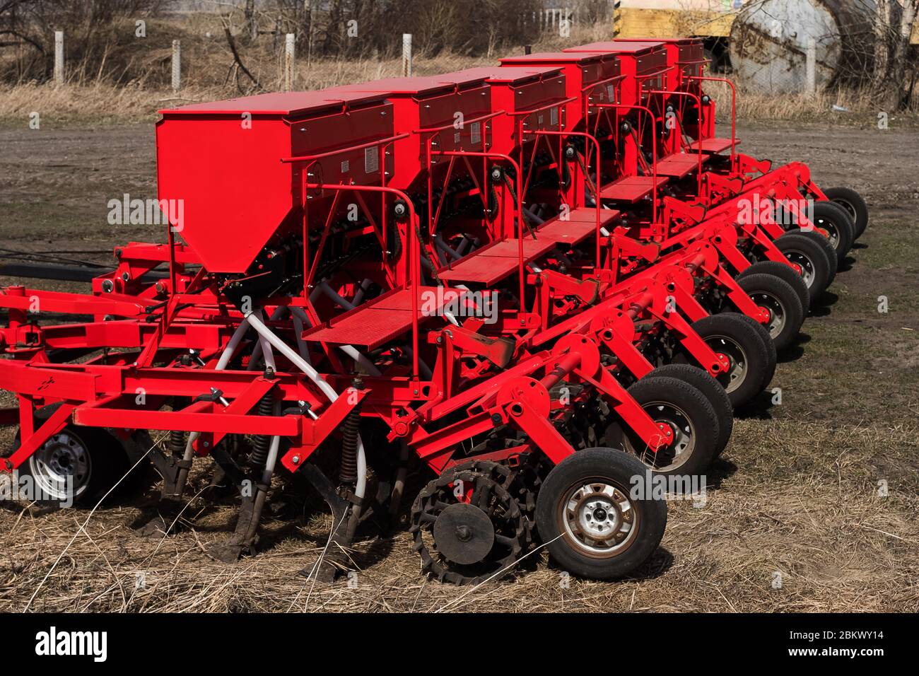Machine moderne de semis de graines. Ensemencement de tracteurs agricoles. Charrue rouge pour moissonneuse-batteuse. Semis de cultures dans les champs agricoles au printemps. Banque D'Images