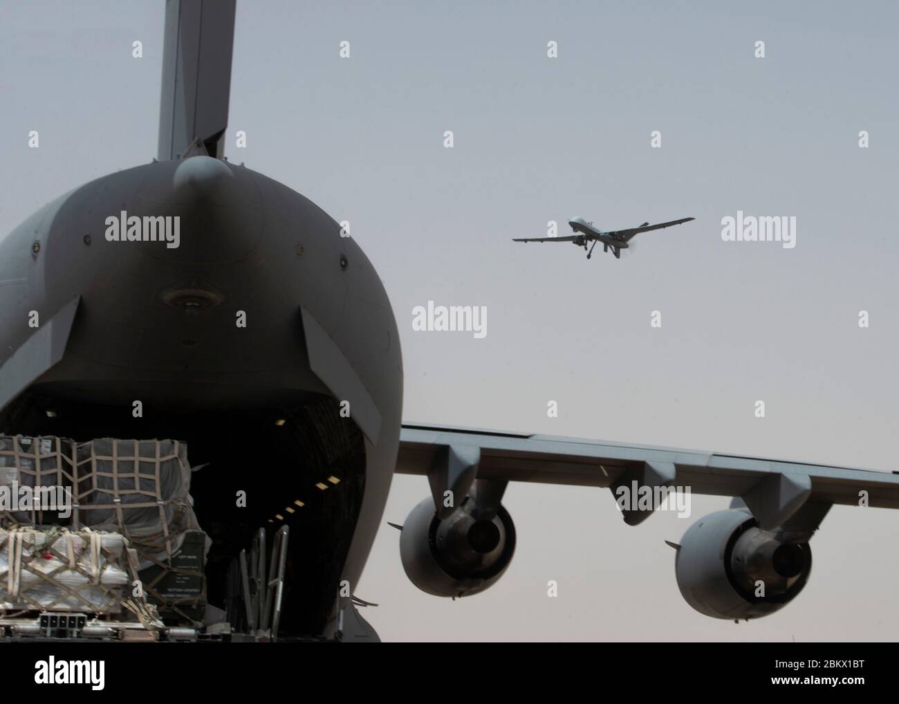 Un MQ-9 Reaper actuellement déployé dans la 386e Escadre expéditionnaire aérienne est lancé alors qu'un C-17 Globemaster III est chargé de marchandises avant de prendre son départ à la base aérienne Ali Al Salem, au Koweït, le 2 mai 2020. La 386e AEW est la porte du théâtre du Commandement central des États-Unis et est responsable de fournir une puissance de combat décisive et un soutien sans précédent au théâtre. (ÉTATS-UNIS Photo de la Force aérienne par le premier Airman Isaiah J. Soliz) Banque D'Images