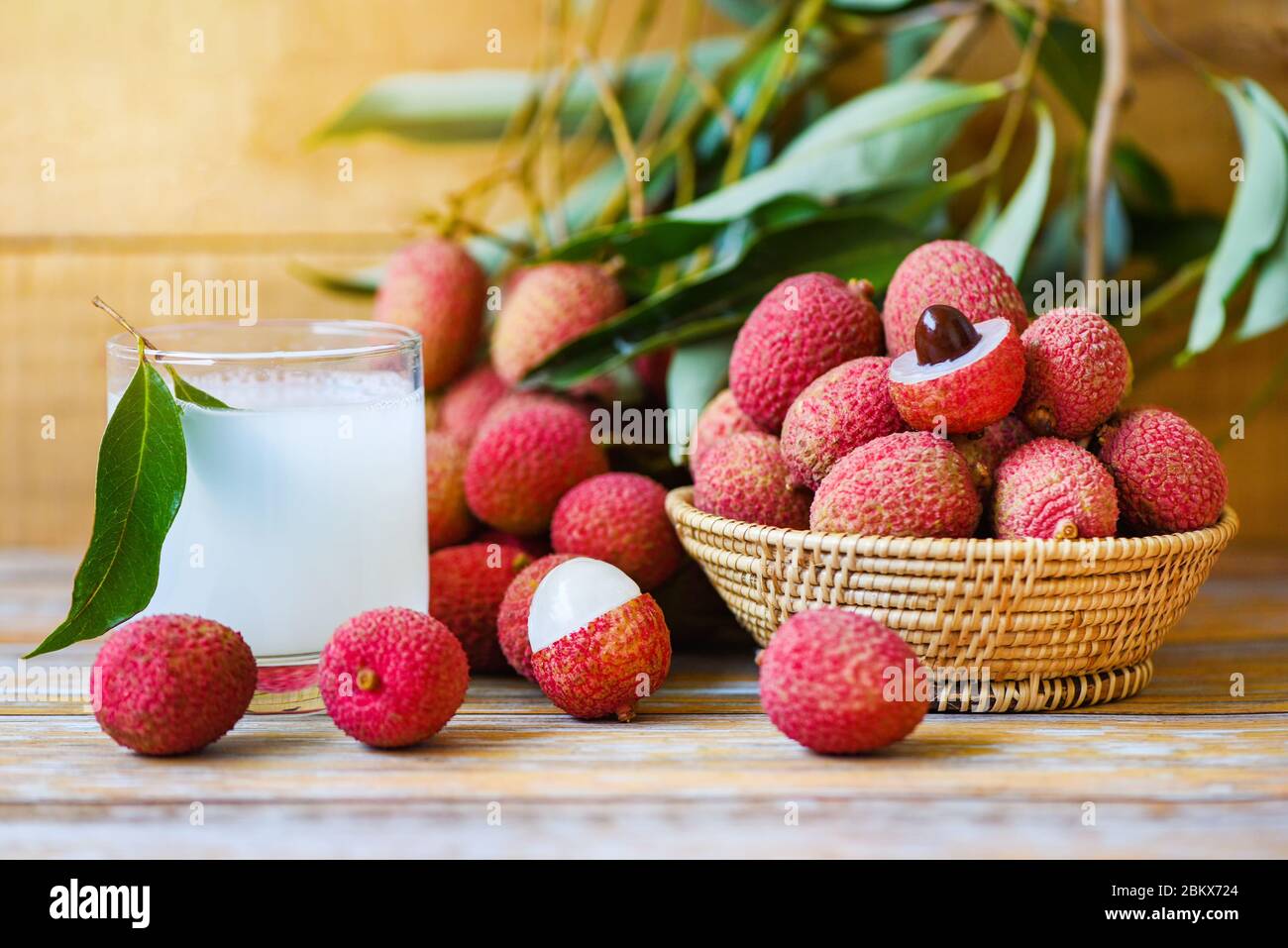 Jus de litchi sur table en bois / boisson fraîche de litchi et tranche épluchée avec des feuilles vertes récolte dans le panier de fruits tropicaux d'arbre été en Thaïlande Banque D'Images