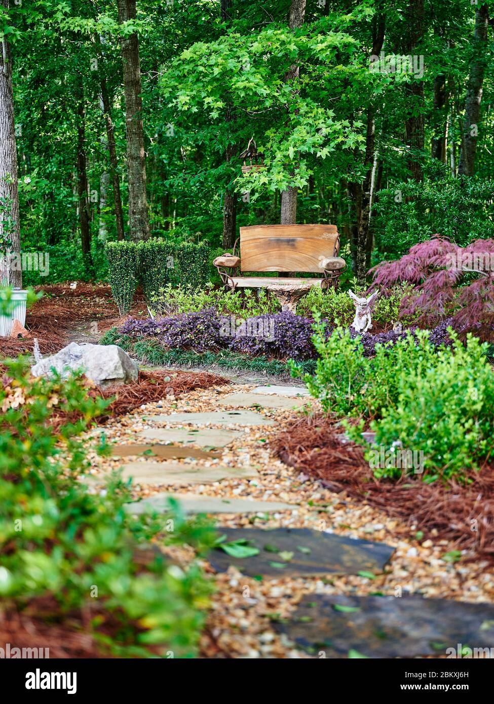 Jardin luxuriant et passerelle en pierre montrant un magnifique aménagement paysager résidentiel. Banque D'Images