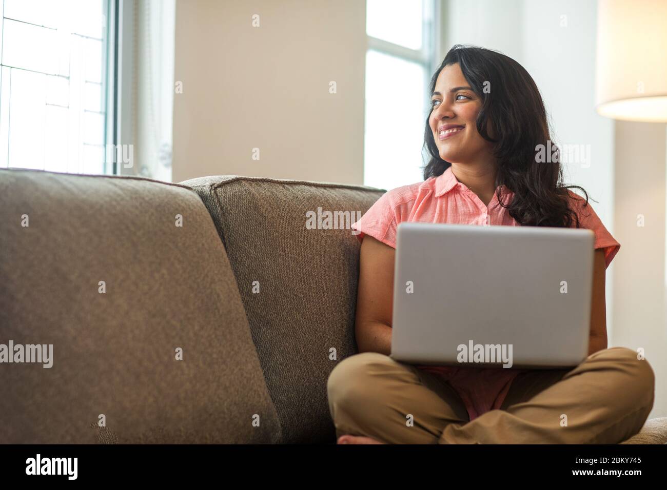 Jeune femme travaillant à la maison assis sur un canapé. Banque D'Images