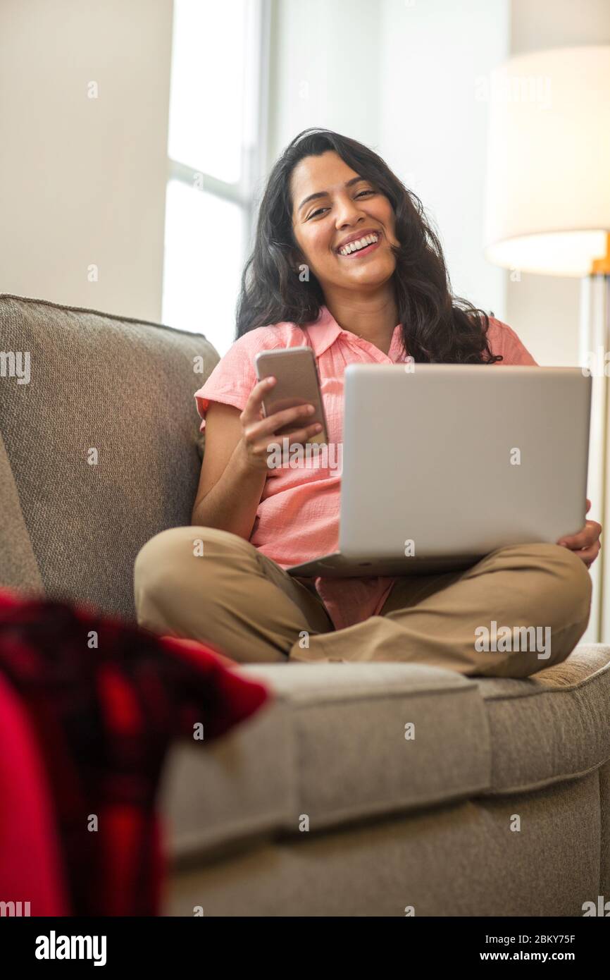 Jeune femme travaillant à la maison assis sur un canapé. Banque D'Images