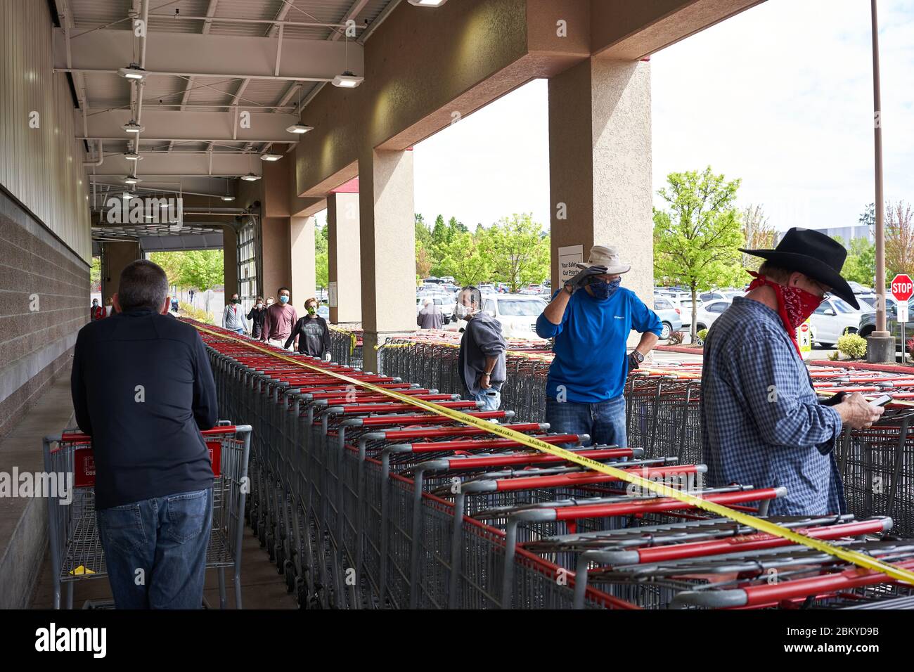 Les acheteurs qui ont des couvre-visage s'alignent à l'extérieur d'un magasin Costco et pratiquent la distanciation sociale, car le magasin limite l'occupation, le mardi 5 mai 2020. Banque D'Images