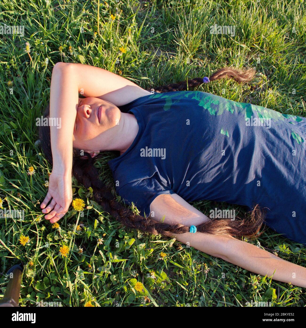 Jeune femme dehors allongé sur le terrain pendant le coucher du soleil Banque D'Images