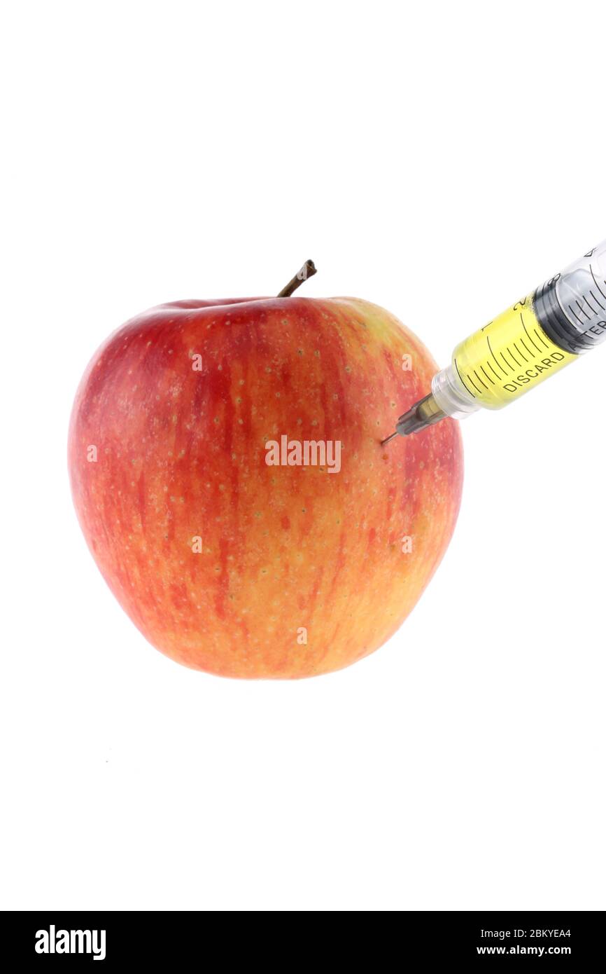 Injection dans une pomme. Une main dans un gant médical avec une seringue sur fond blanc. Aliments modifiés génétiques. Injection d'OGM. Banque D'Images