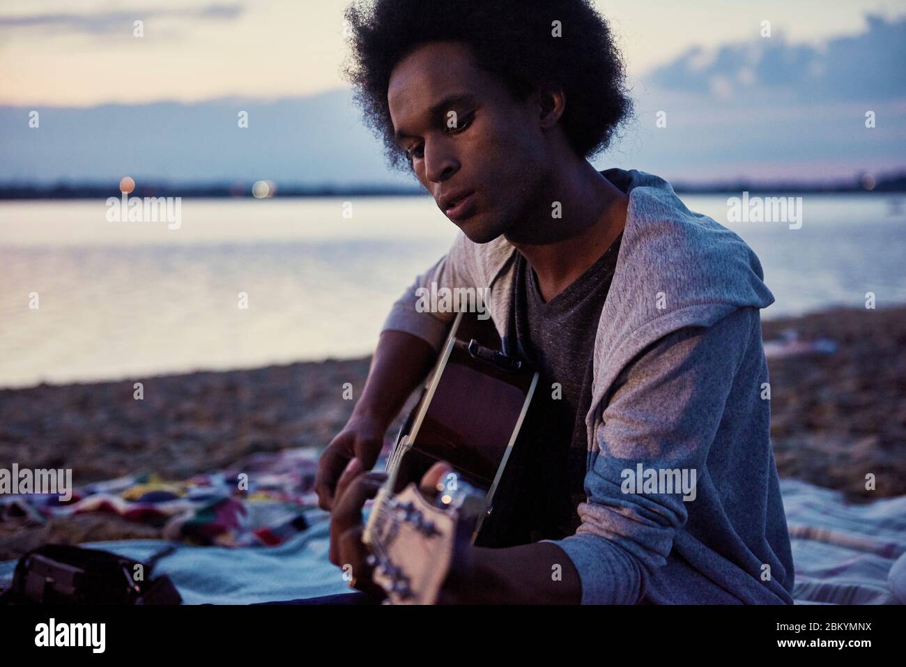 Homme africain jouant de la guitare sur la plage la nuit Banque D'Images