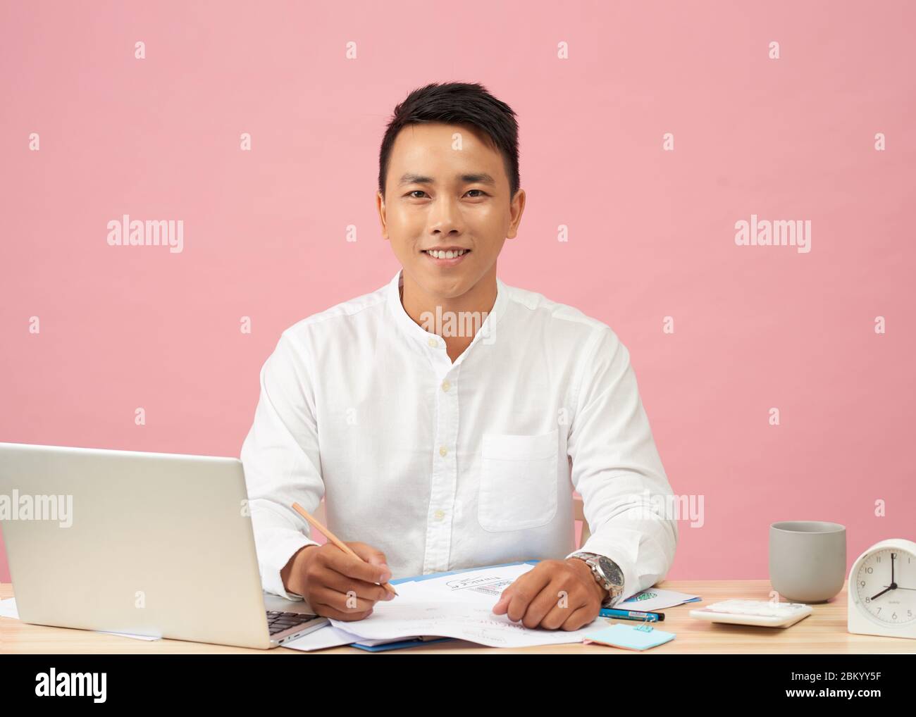 Young attractive asian businessman using laptop sitting on desk in office Banque D'Images