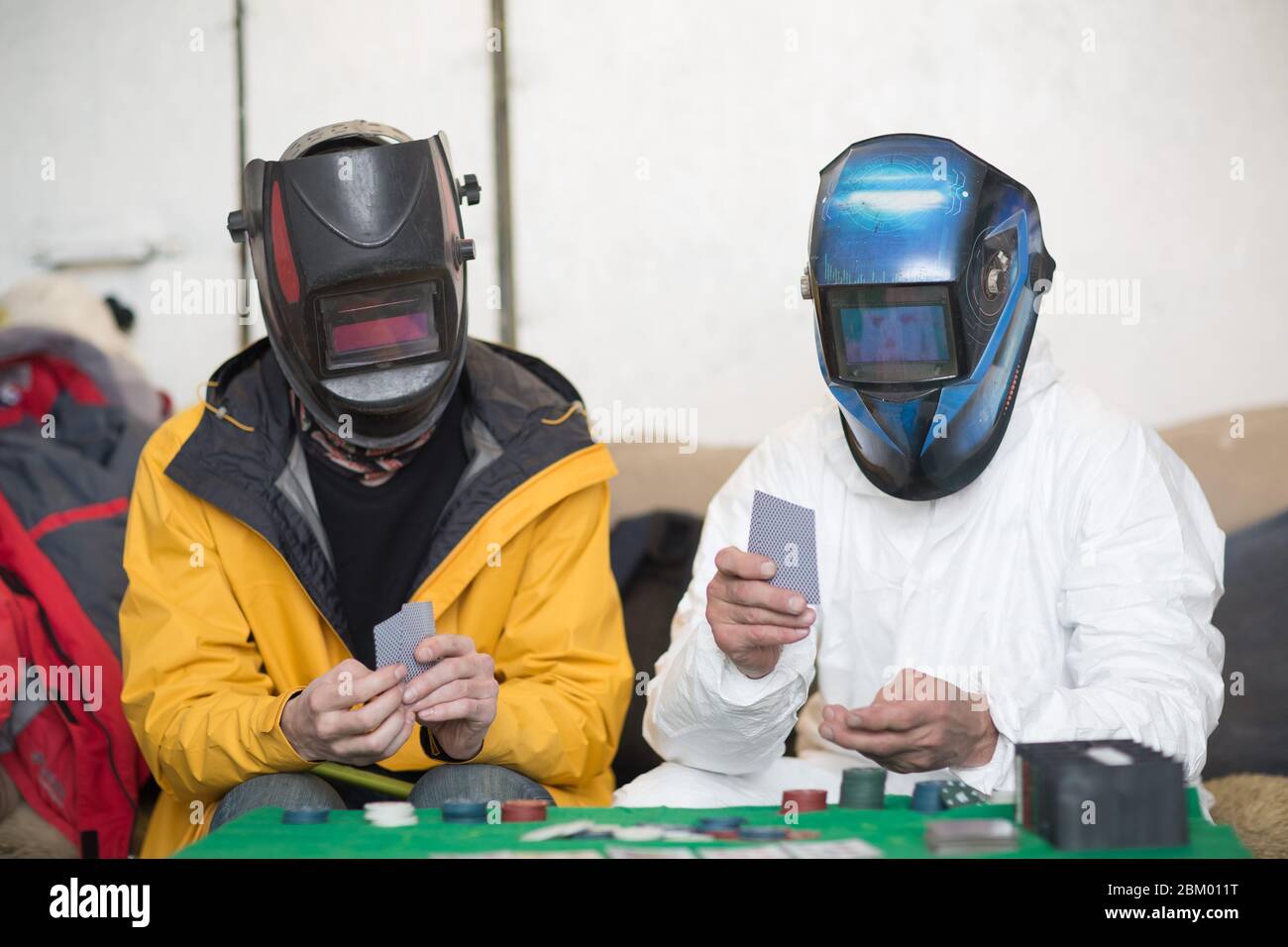 Deux soudeurs dans les masques de soudage jouent au poker Banque D'Images