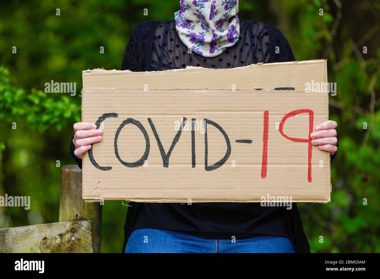 Jeunes femmes tenant une affiche en carton Covid-19 Banque D'Images