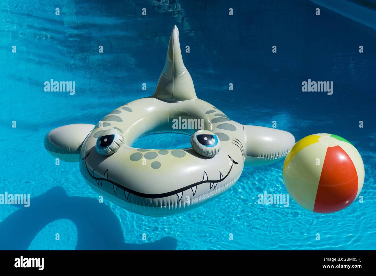 Anneau en caoutchouc gonflable de requin et ballon de plage gonflable flottant dans une piscine de villa à Paphos sur l'île de Chypre Banque D'Images