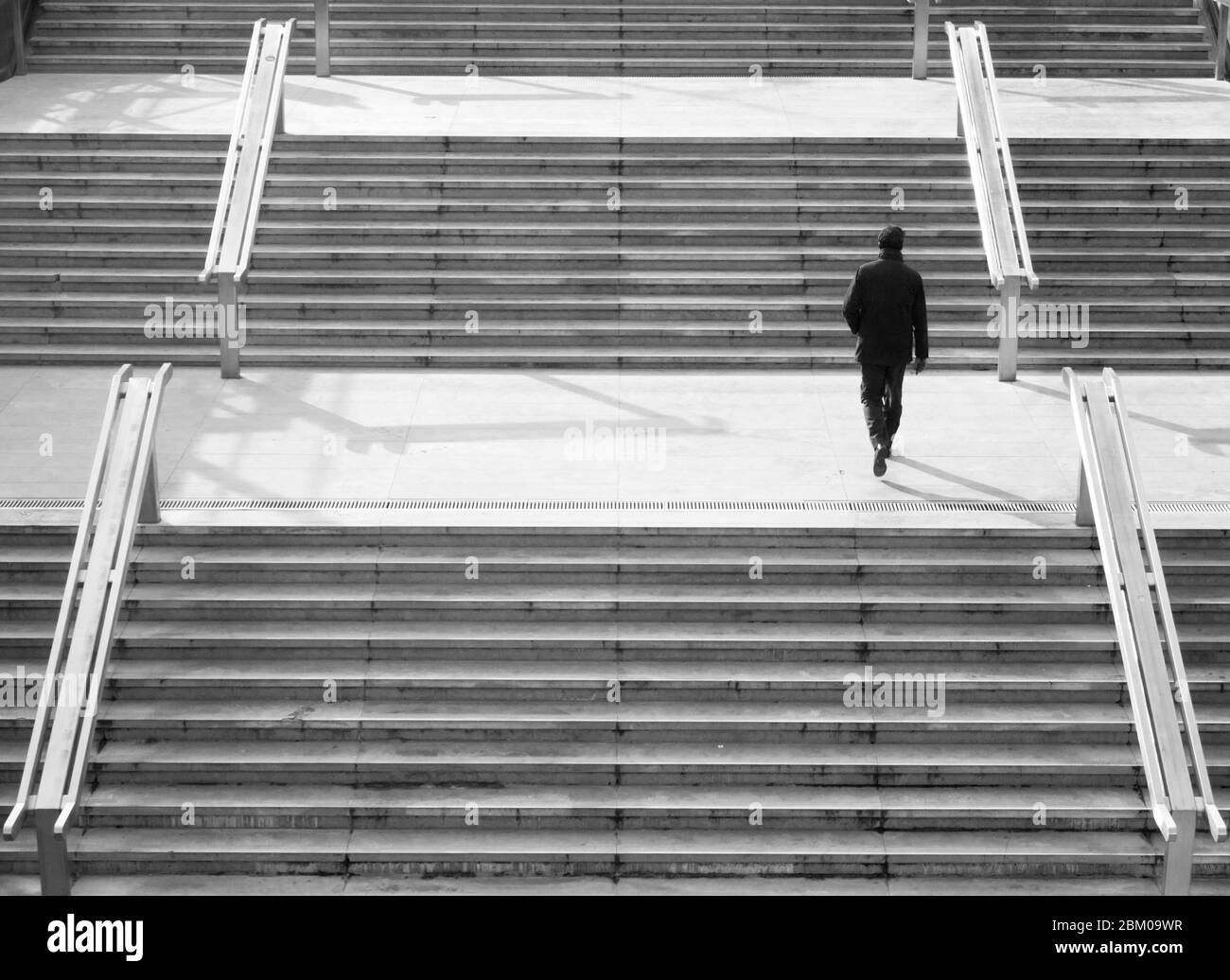 Homme marchant dans un escalier moderne dans une ville - photo monochrome Banque D'Images