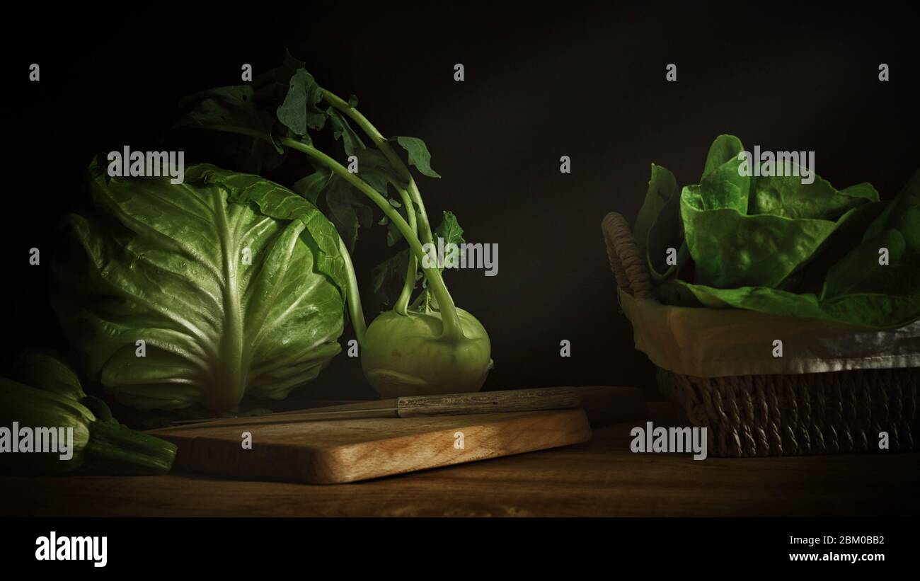 Gros plan de légumes frais verts chou-navet chou-courgettes et courgettes sur table en bois et planche à découper en bois en photographie par faible luminosité Banque D'Images