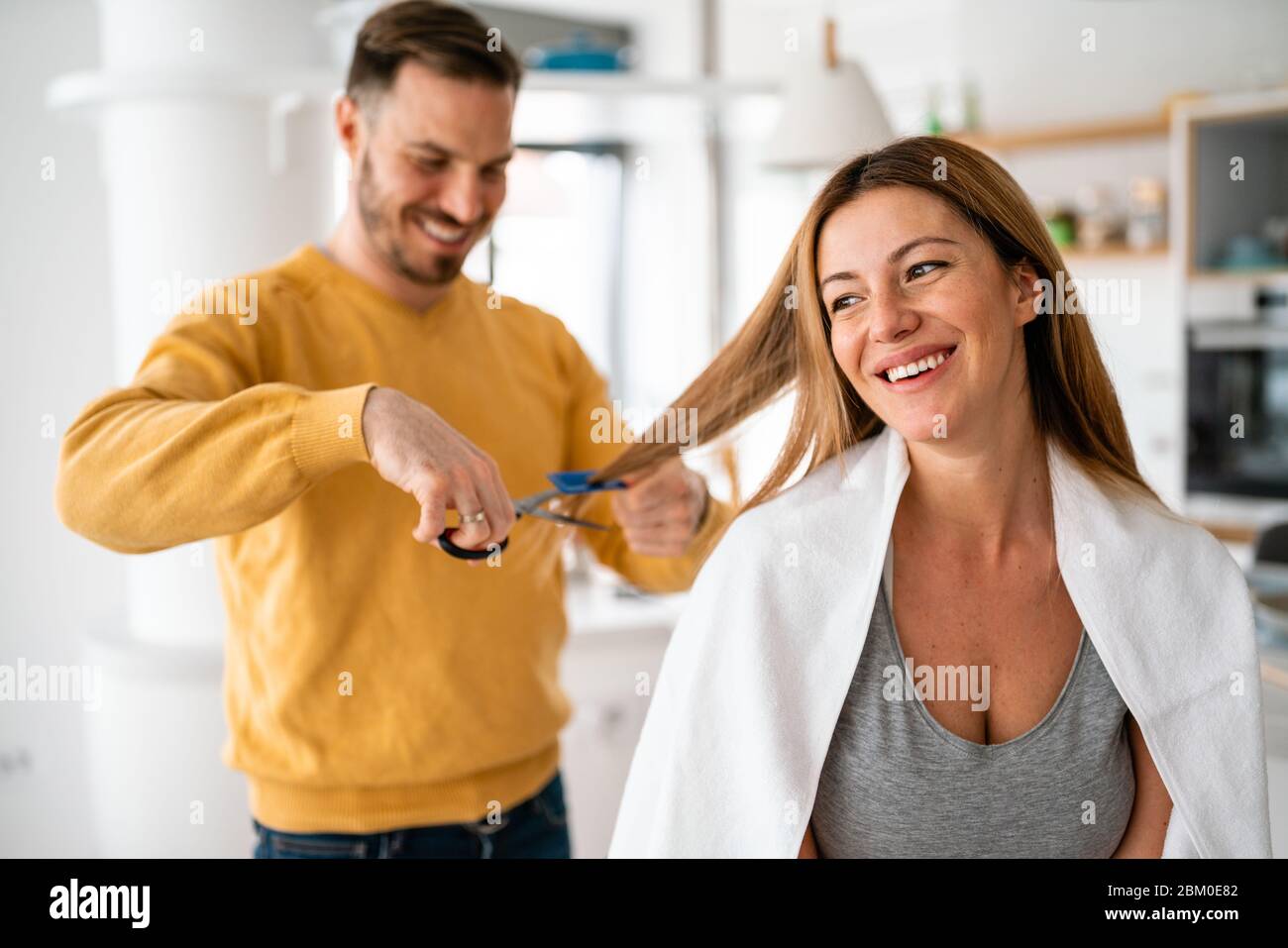 Couple ayant coupé les cheveux à la maison pendant la quarantaine de la pandémie de coronavirus, coiffure en ligne sur comprimé Banque D'Images