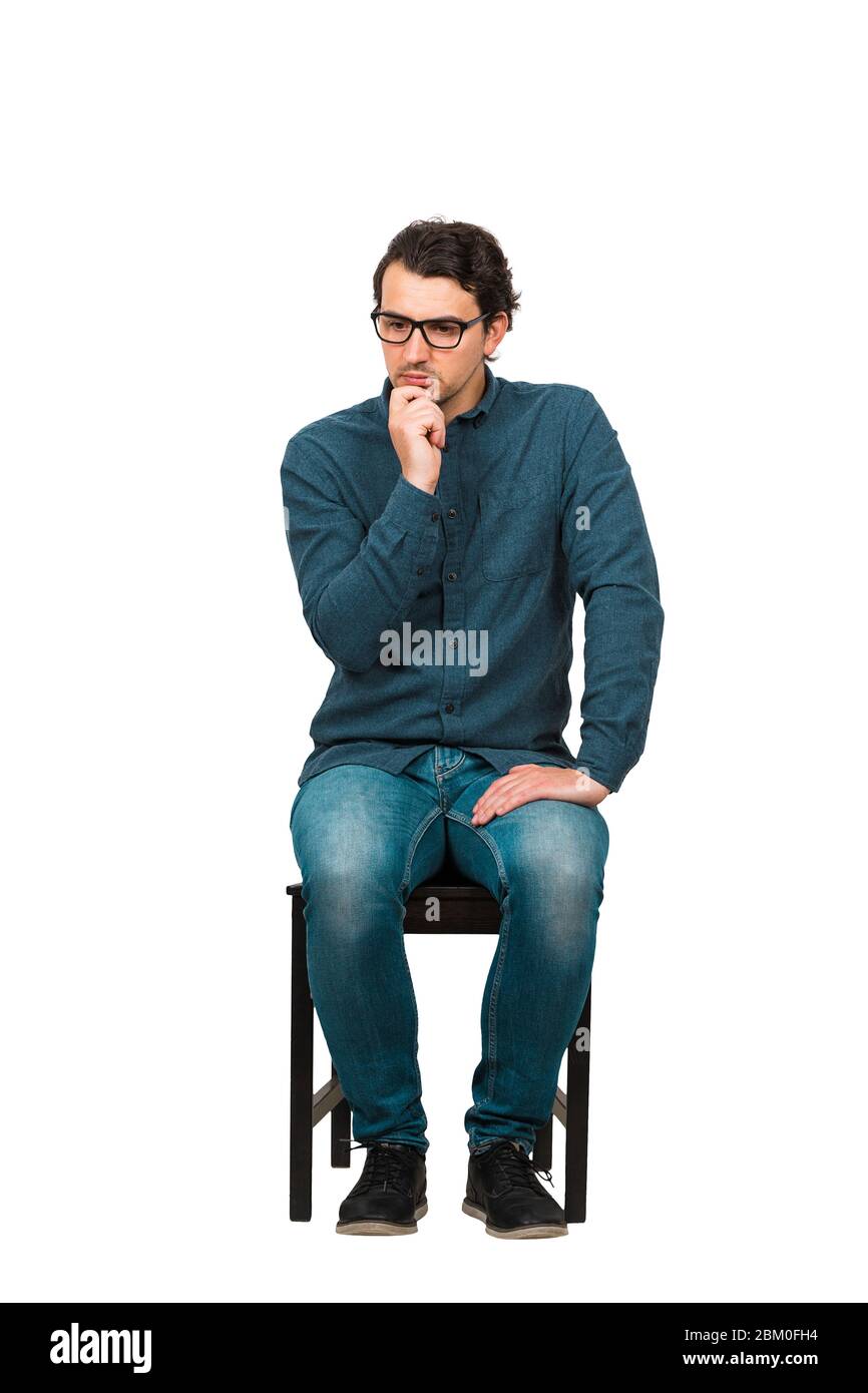 Toute la longueur d'homme d'affaires attentionné garde la main sous le menton, assis sur une chaise isolée sur fond blanc. Employé d'affaires, porte des lunettes, regardant Banque D'Images