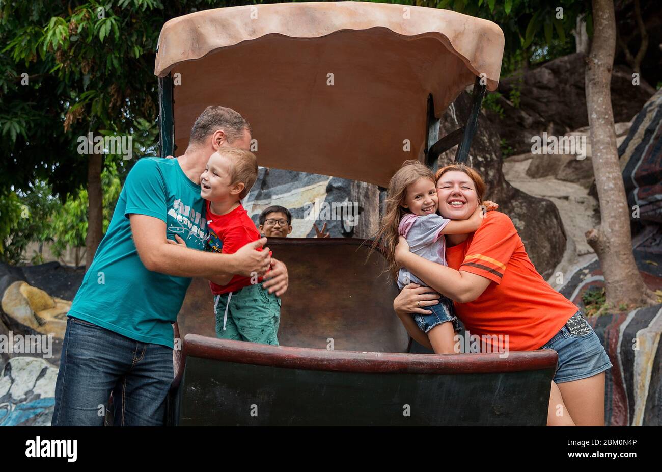 famille heureuse de père, mère et deux enfants, bébé fils et fille et un autre garçon dans le parc. Banque D'Images