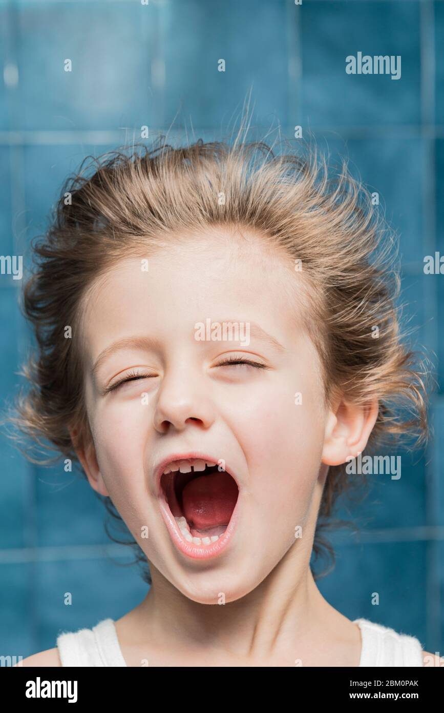 Un enfant dans la salle de bains sèche ses cheveux avec un sèche-cheveux, en faisant des gestes. Banque D'Images