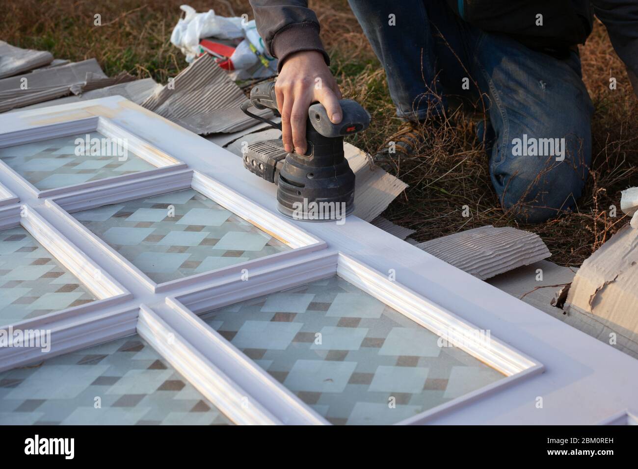 restauration de vieilles portes en bois, nettoyage de surface avec un outil de meulage, préparation pour la peinture. Banque D'Images