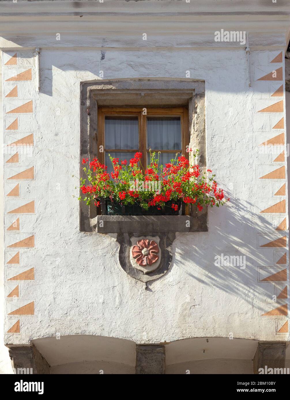 Fenêtre avec fleurs rouges sur un fond de mur blanc d'un bâtiment. Cesky Krumlov, république tchèque. Banque D'Images