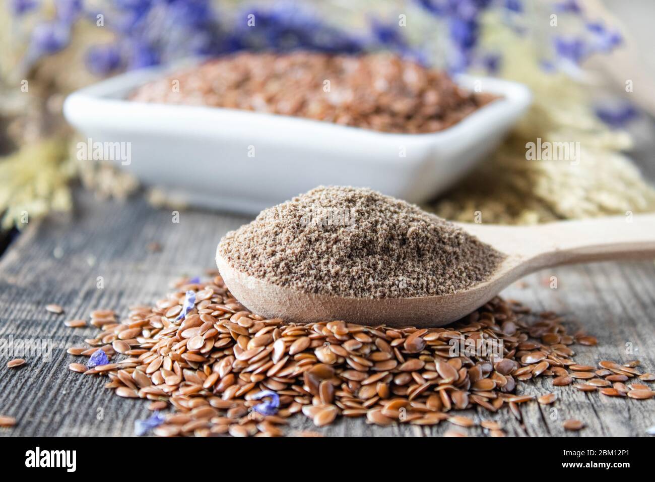 Graines de lin écrasées dans une cuillère en bois sur une pile de lin. Les graines de terre sont utilisées pour prévenir les maladies cardiaques et être en surpoids. Banque D'Images