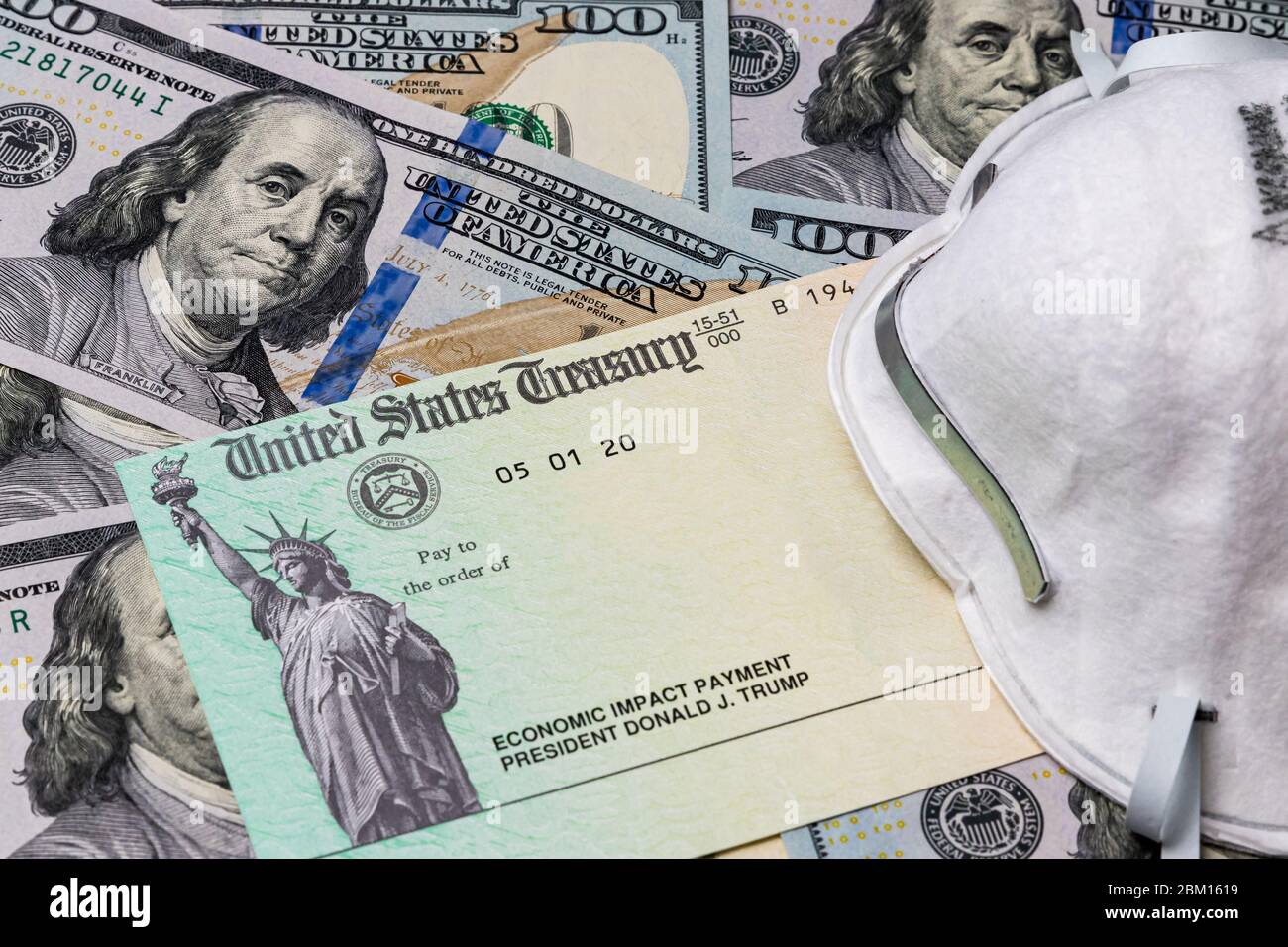 Masque N95, chèque de trésorerie pour le paiement de l'impact économique et billets de 100 dollars. Concept de paiement de la stimulation pandémique du coronavirus Covid-19. Banque D'Images