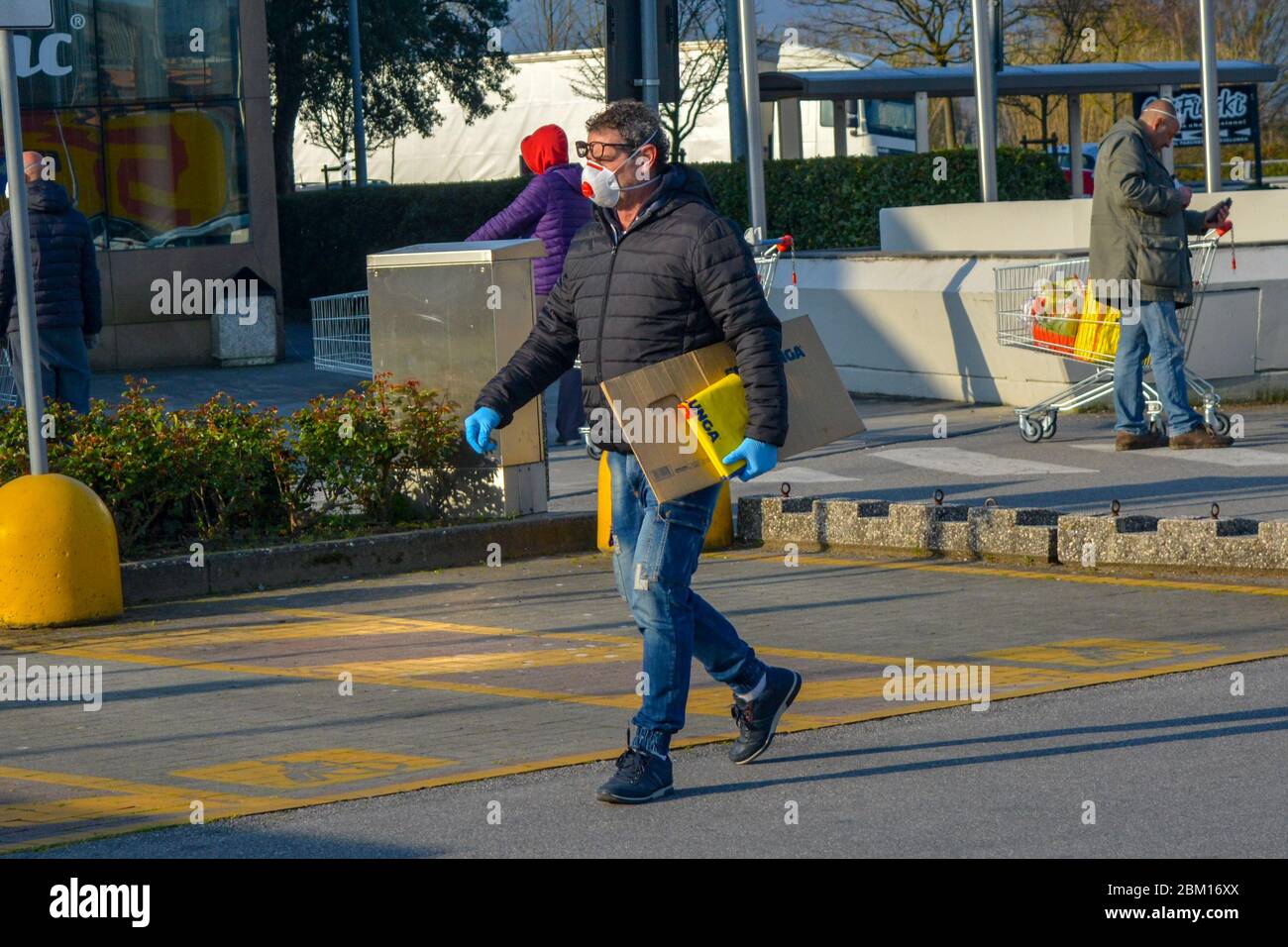 Toscana, Italie 03/21/20 - vieil homme italien portant un masque chirurgical de protection contre le coronavirus avec des sacs d'achats sous son bras. Achat panique, anxiété, peur Banque D'Images