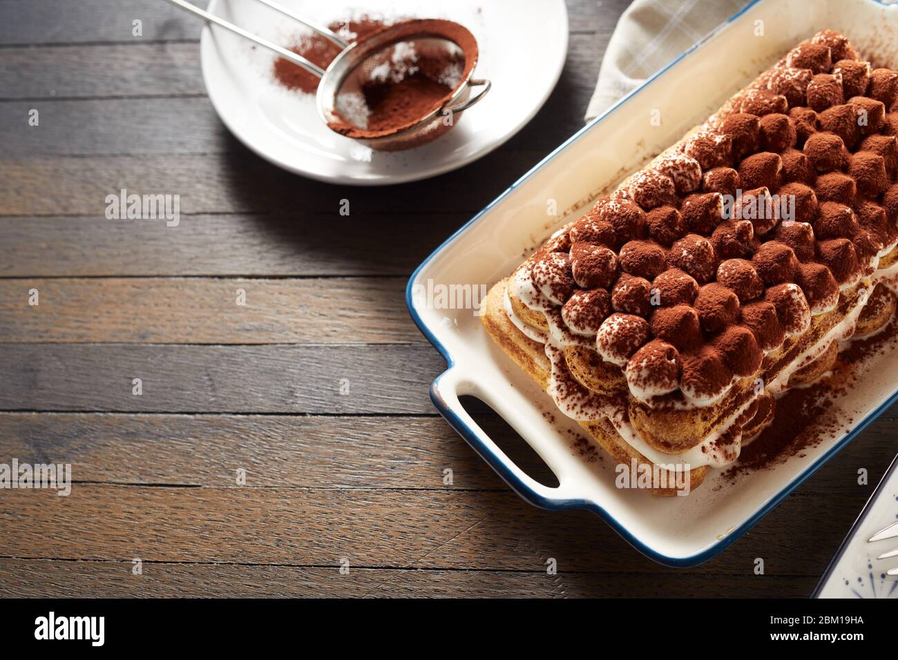 Délicieux dessert italien tiramisu avec fromage marscapuone et biscuits de boudoir parsemés de cacao servis sur une table avec espace copie Banque D'Images