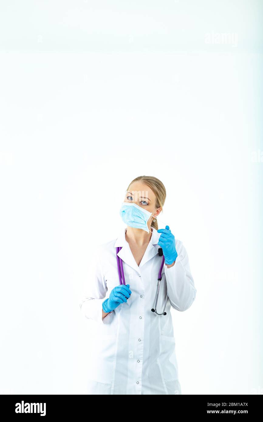 le médecin infirmière met un masque de protection. Une infirmière dans un masque respiratoire. Mettre des masques. Portez des gants. Beau docteur blond montre comment mettre sur un protec Banque D'Images