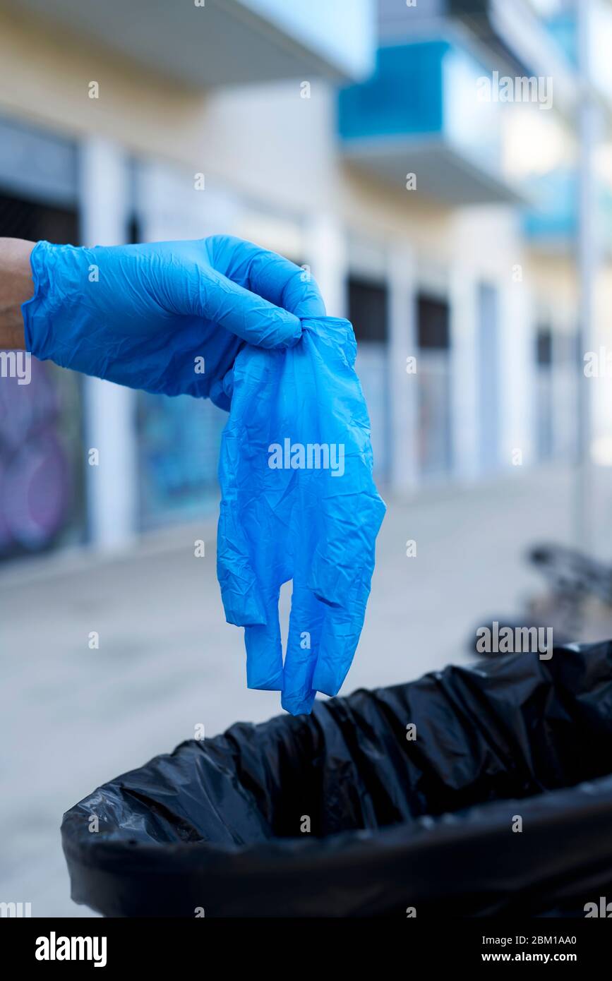 gros plan d'un homme qui jette un gant en latex bleu usagé à la poubelle  dans la rue Photo Stock - Alamy