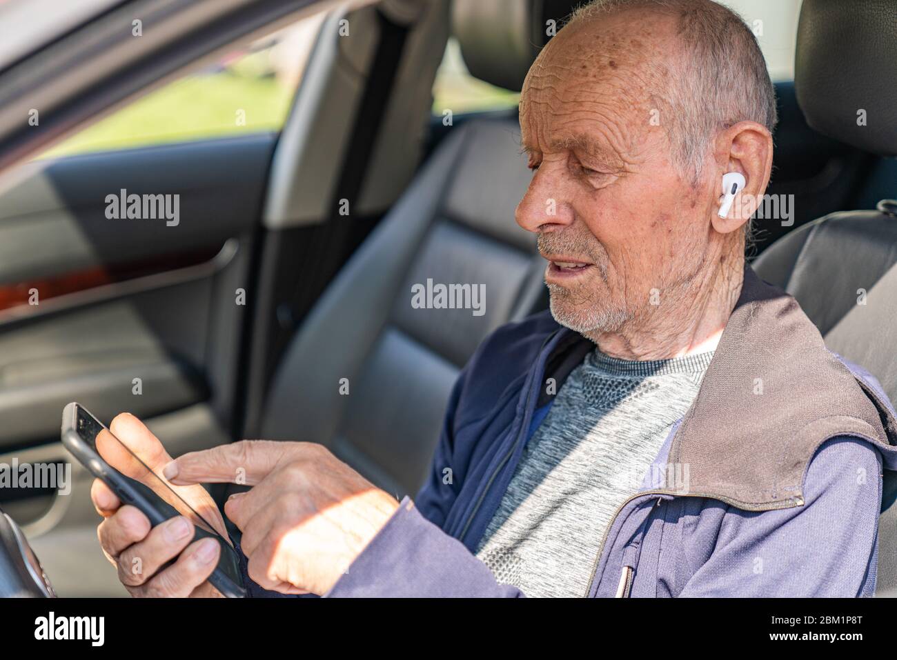 Joyeux, joyeux homme âgé voyageur assis dans la voiture et de choisir l'endroit pour voyager au téléphone Banque D'Images