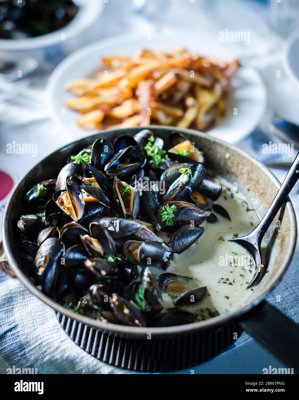 Moules frites – palourdes aux frites. Cuisez les frites dans une casserole noire avec des frites en arrière-plan. Banque D'Images