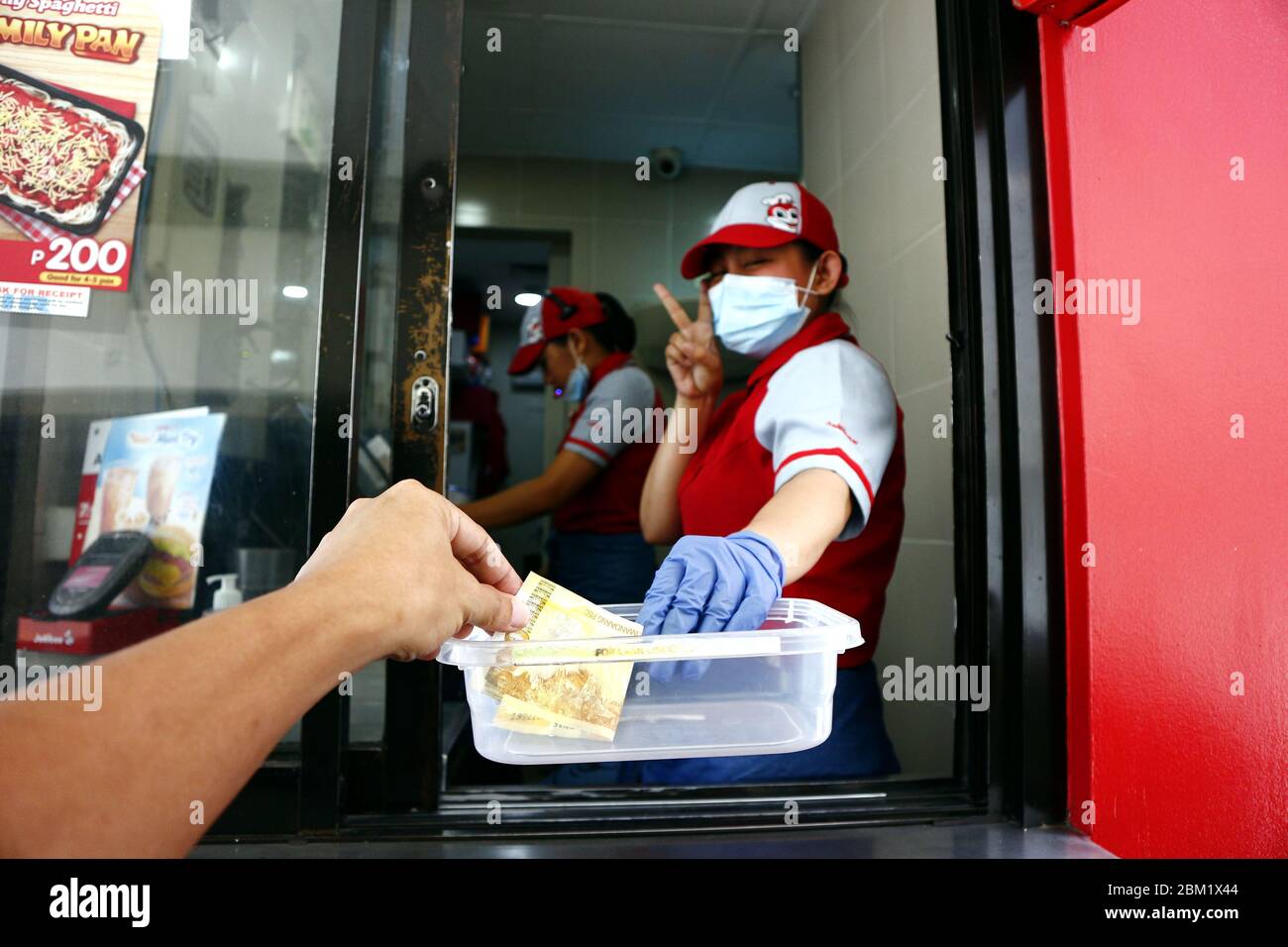 Antipolo City, Philippines - 5 mai 2020 : l'employé d'un restaurant de restauration rapide reçoit le paiement d'un client au guichet du drive pendant le Covid Banque D'Images