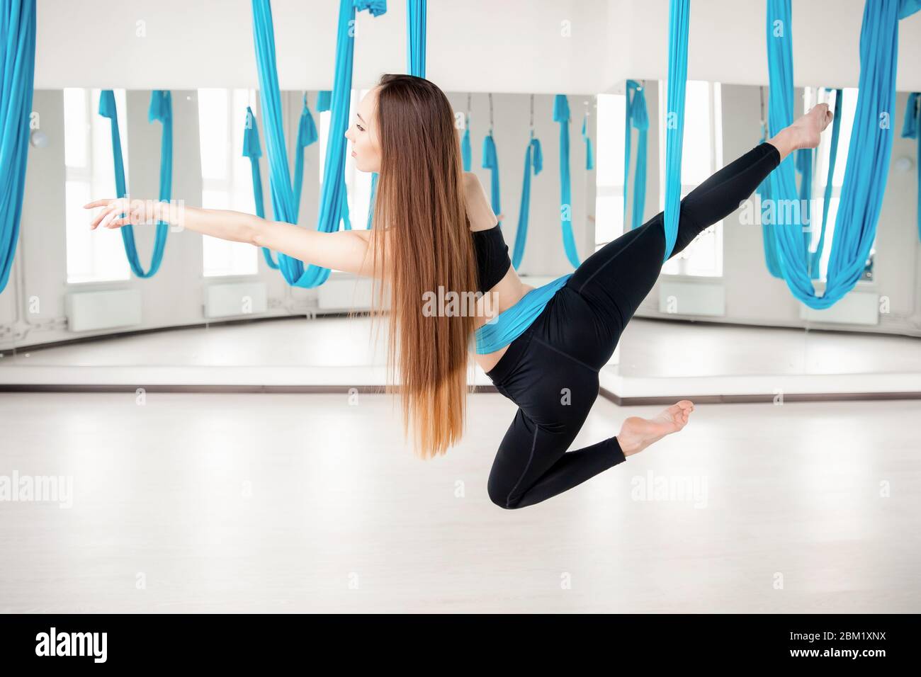 Yoga aérien dans la salle de sport blanche. Jeunes femmes belles pratiquant  des pilotes étirements dans un hamac bleu Photo Stock - Alamy