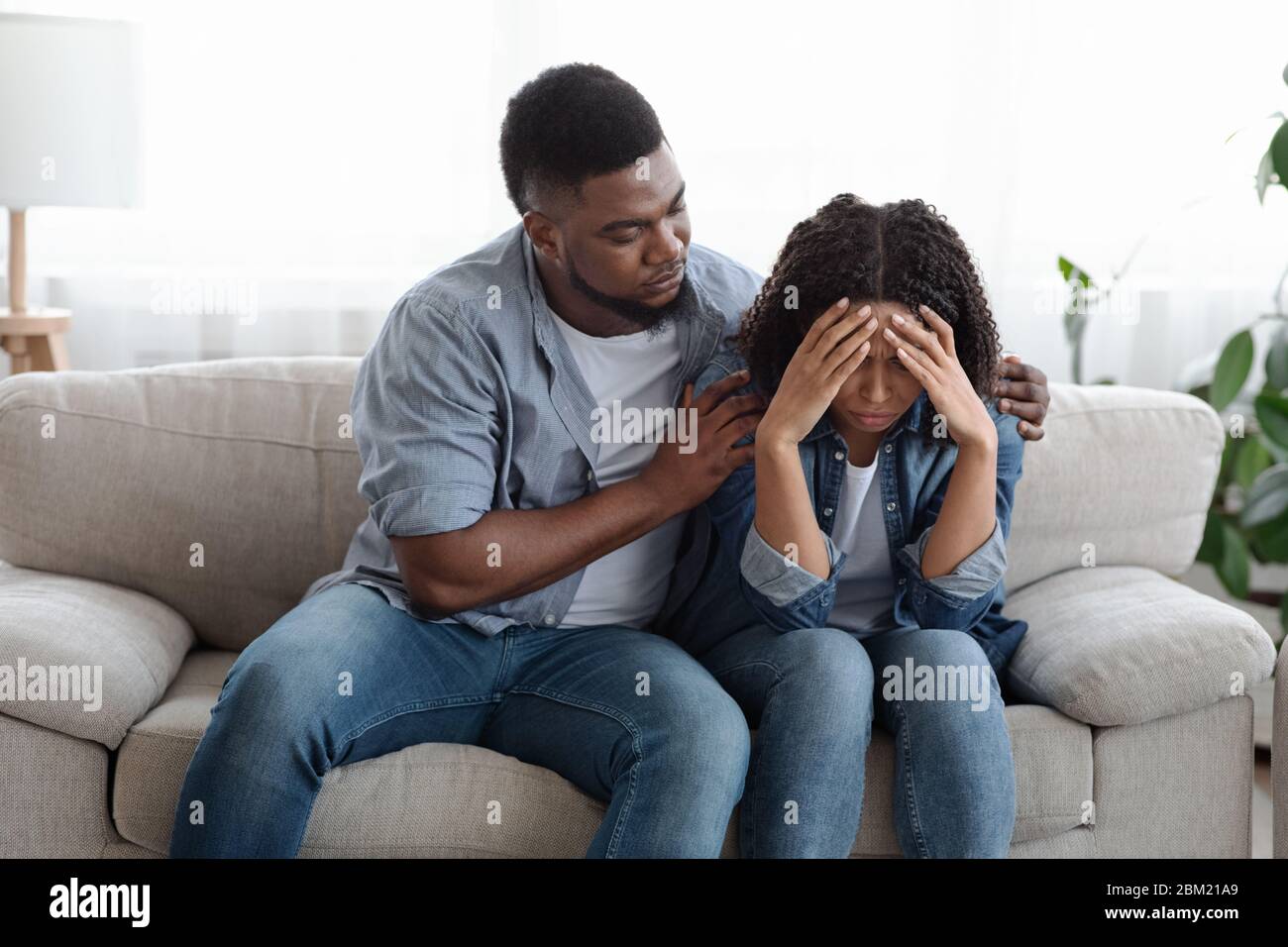Homme noir de soutien réconfortant sa petite amie contrariée à la maison, exprimant de l'empathie Banque D'Images
