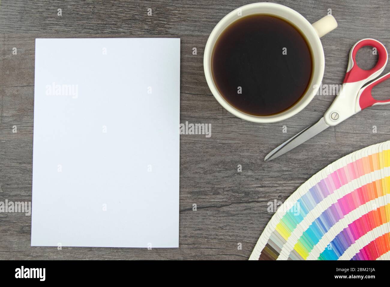 Vue de dessus de page blanche vide, crayon élégant, cartes de gamme de couleurs, ciseaux et tasse à café sur planche en bois Banque D'Images
