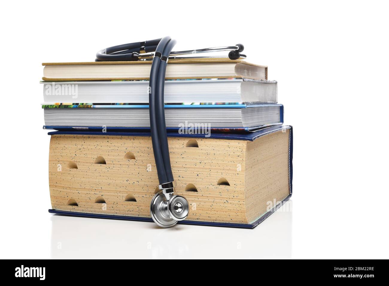 Concept de formation professionnelle médicale. Un stéthoscope drapé sur une pile de livres médicaux, isolés sur du blanc. Banque D'Images