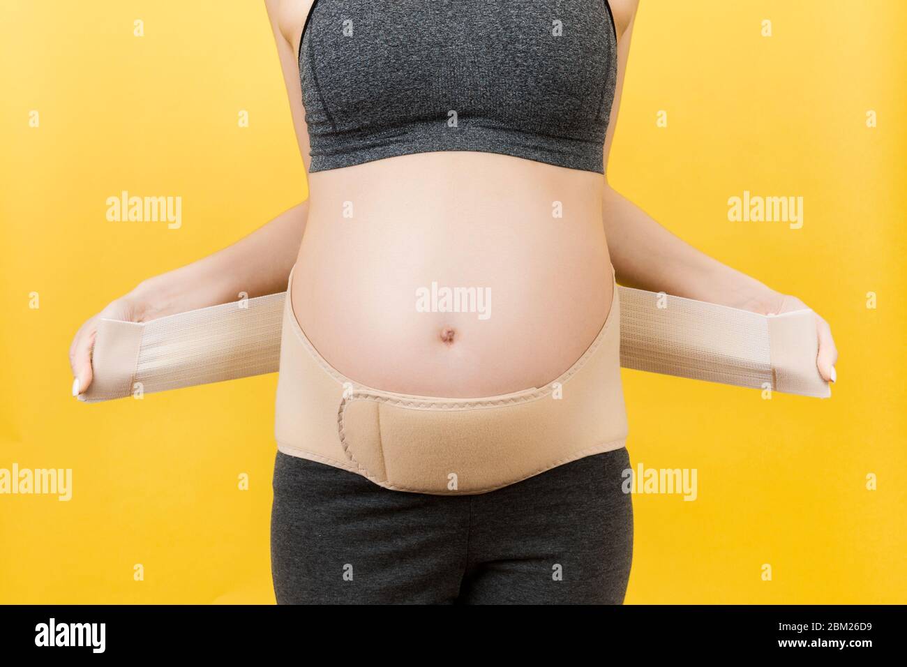 Image rognée de la femme enceinte portant un pansement orthopédique pour  réduire la douleur dans le dos sur fond jaune avec espace de copie.  Orthopédie abdomen supp Photo Stock - Alamy